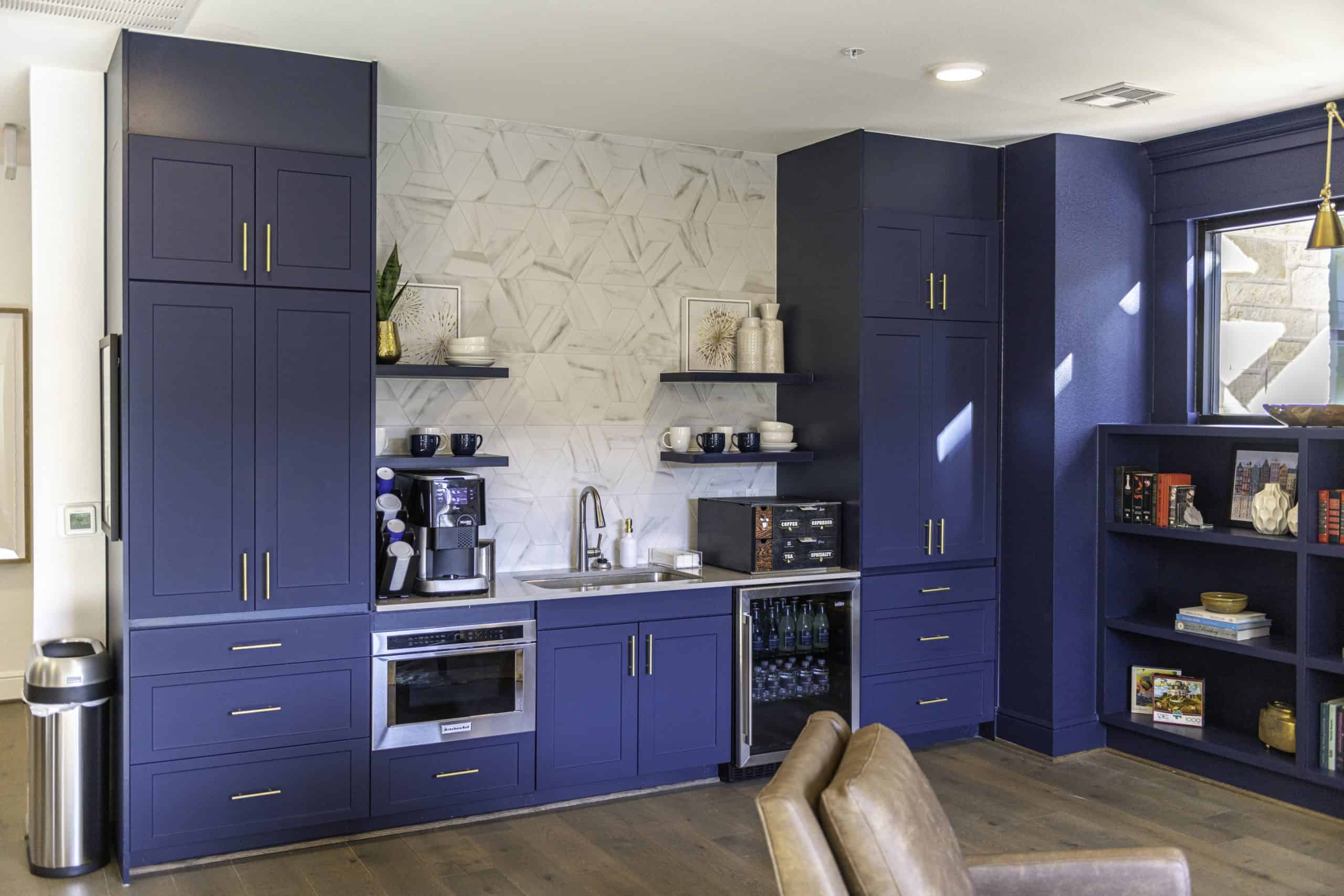 Kitchenette at our senior living apartments in Cypress, featuring blue cabinetry, a sink, and a mini fridge.