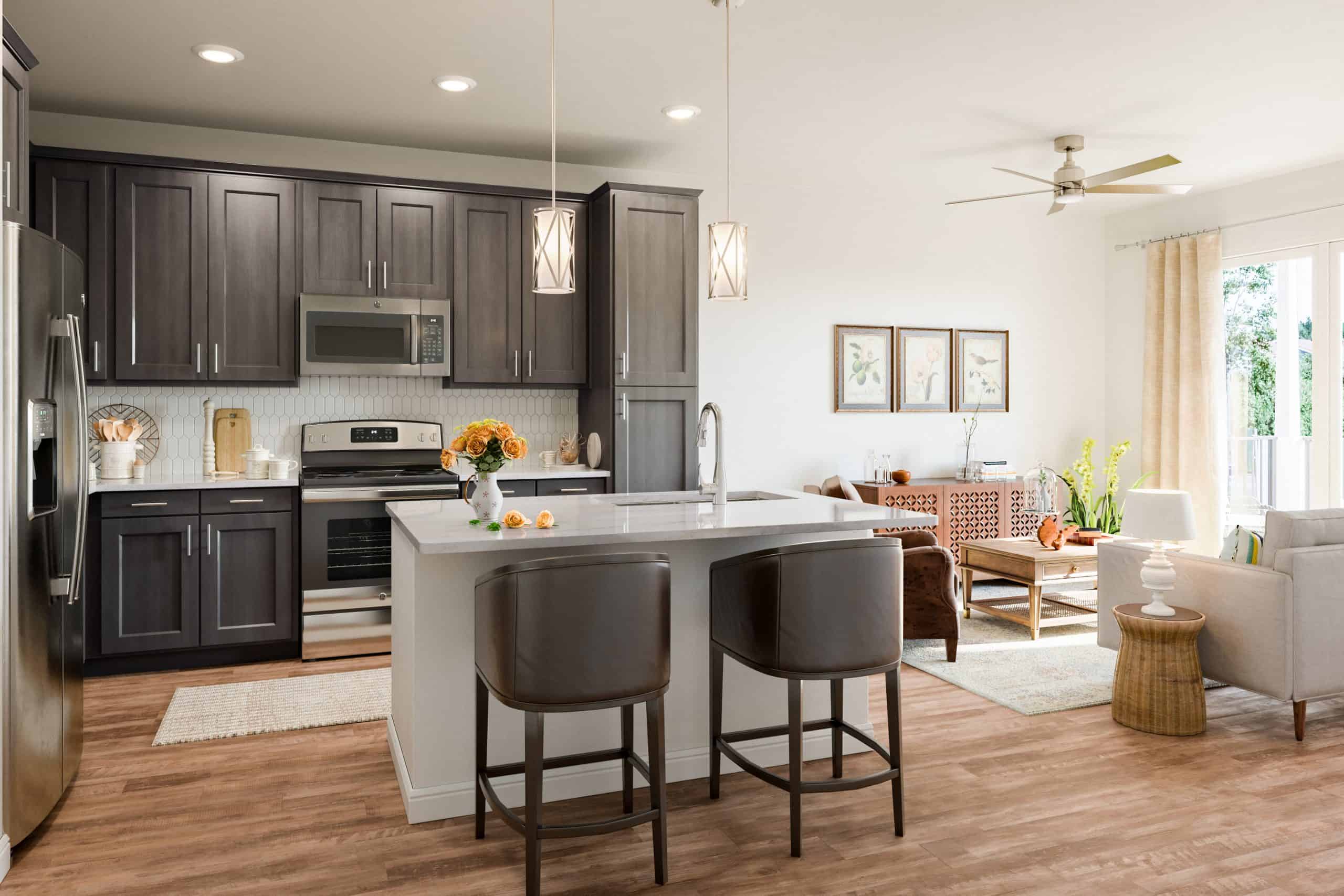 Model kitchen at our 55 and over community in Cypress, featuring wood grain floor paneling and a kitchen island.