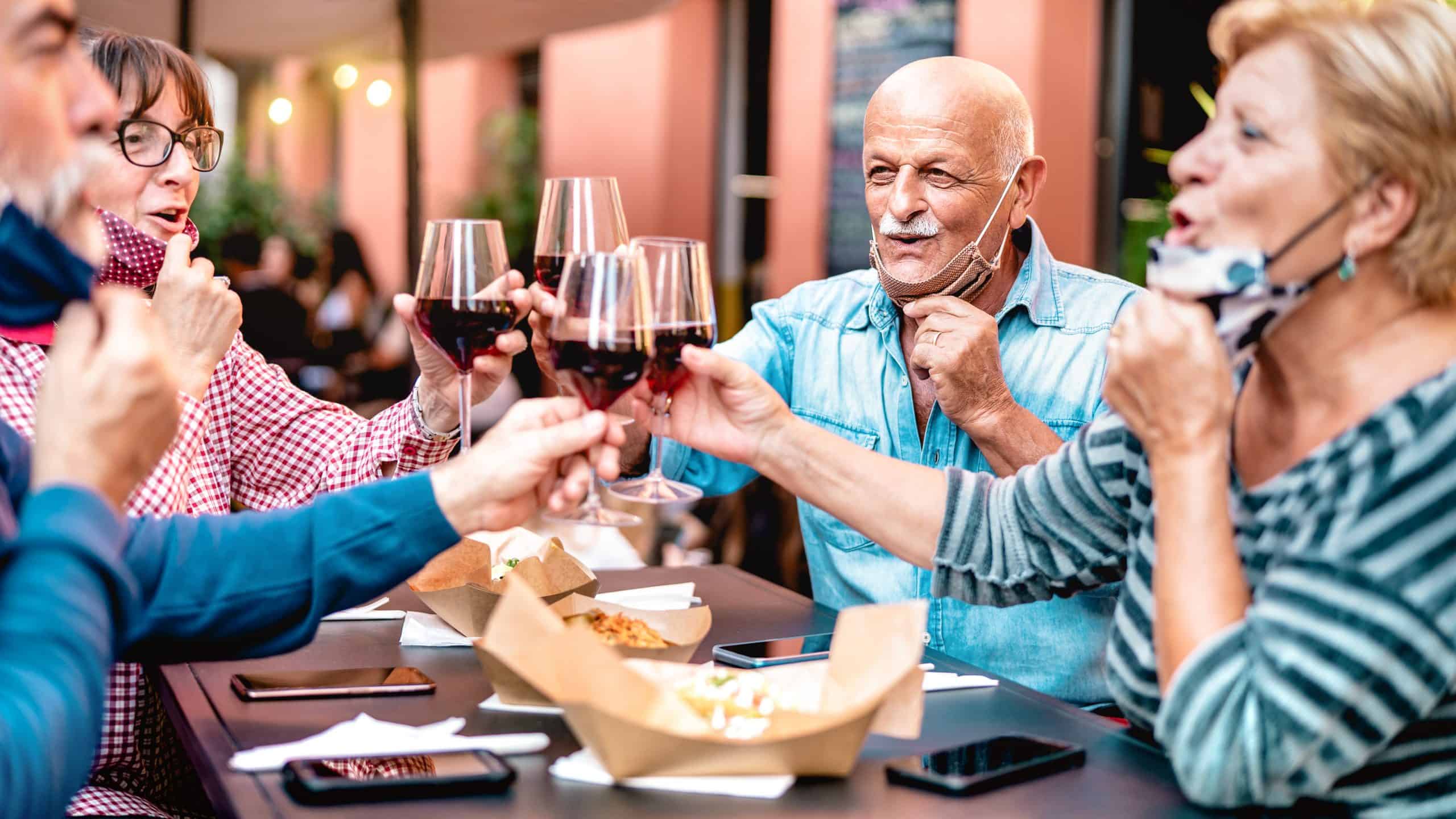 People at an outdoor dining area near or 55 and over community in Cypress, TX. They are in mid-cheers with glasses of wine.